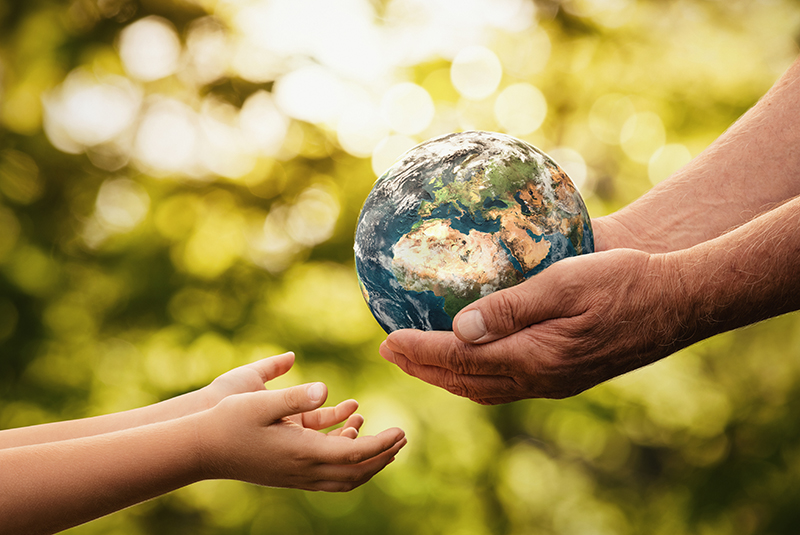 Close up of senior hands giving small planet earth to a child ov